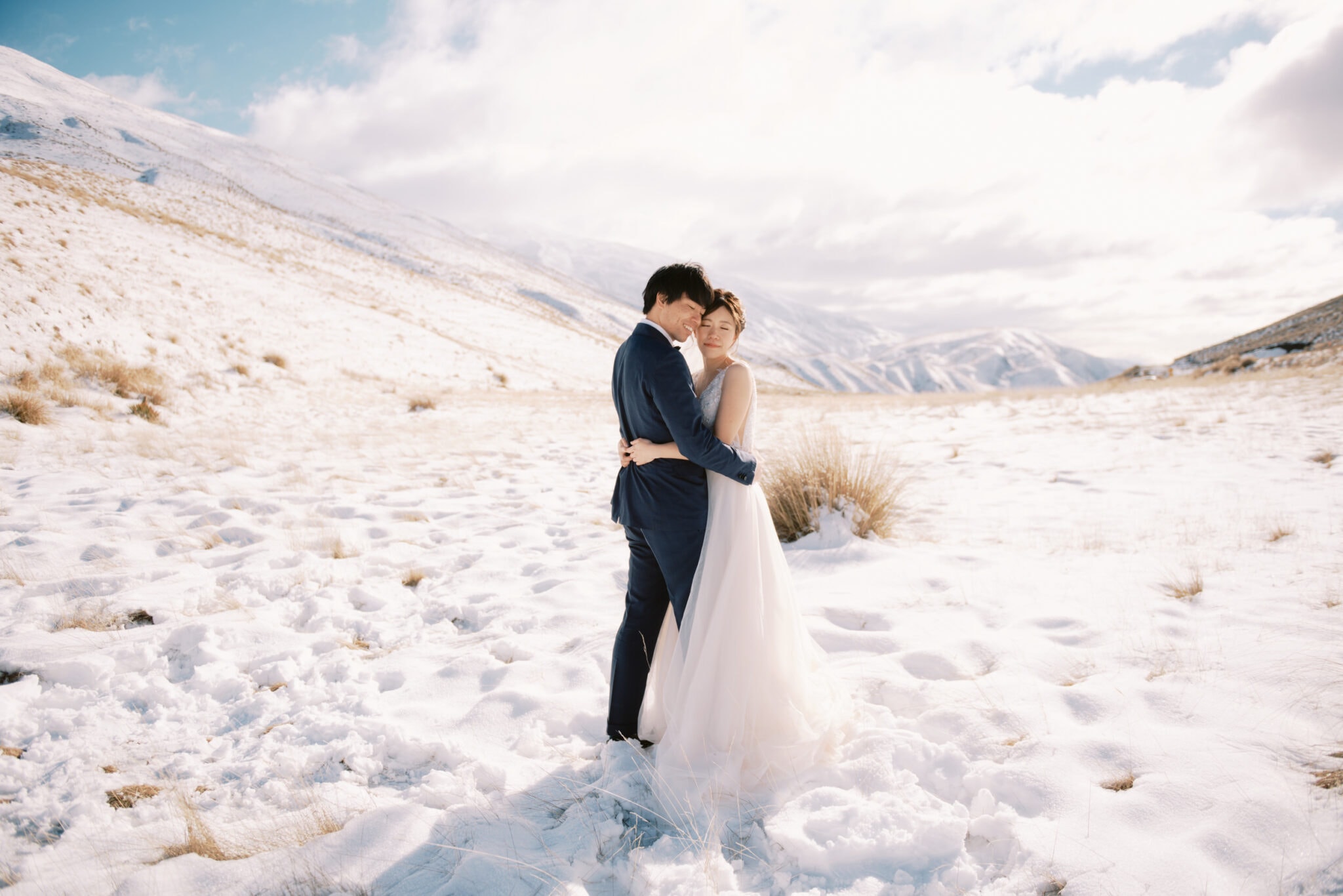 Queenstown Tekapo New Zealand Heli Wedding Elopement Pre-Wedding Shoot Photographer クイーンズタウン　テカポ　ニュージーランド　エロープメント 前撮り　フォトウェディング　結婚式 | A couple embracing in a snowy landscape during their Tekapo pre-weddng shoot.
